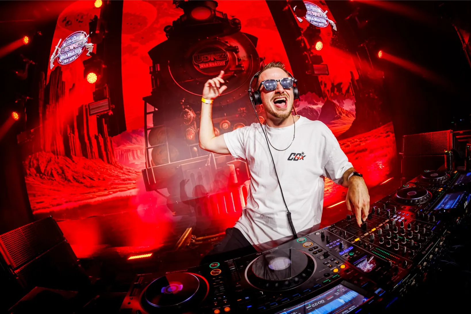 DJ tijdens een optreden met rode podiumverlichting bij UDNZ