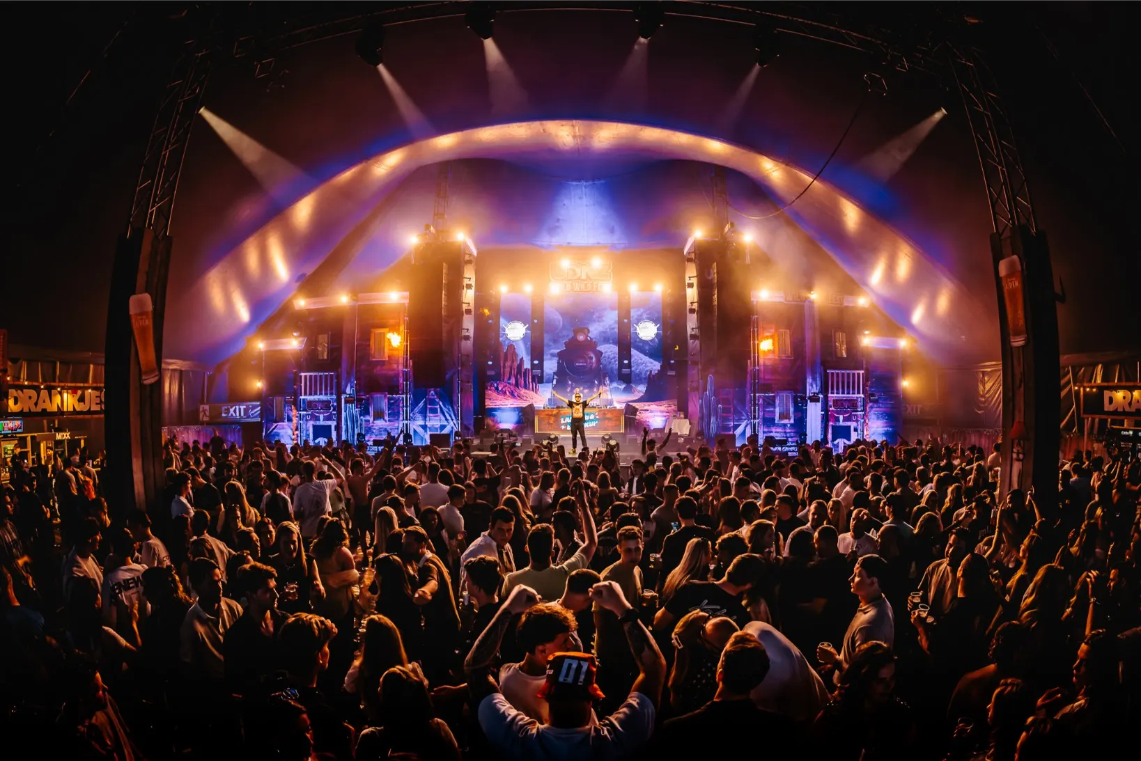 Groot podium met warme verlichting en een volle festivaltent bij UDNZ